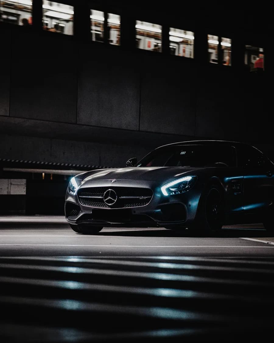 A dark luxury car lit from the side in an underground garage in Dubai