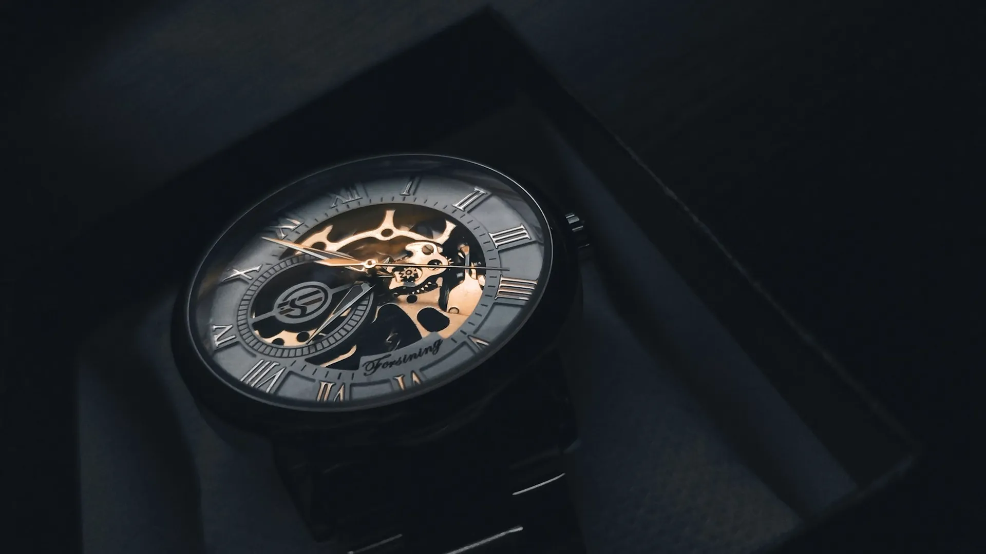 A luxury wristwatch resting on a dark presentation box
