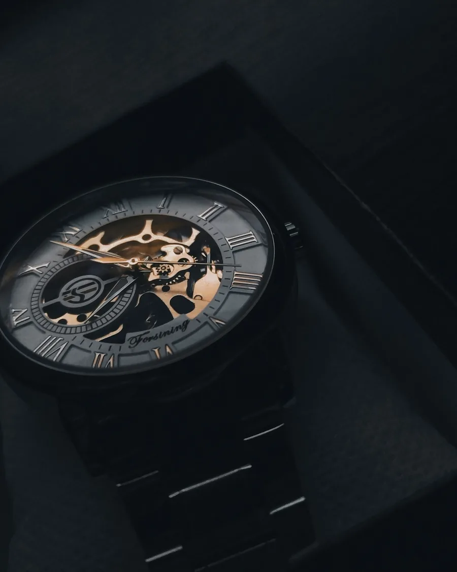 A luxury wristwatch resting on a dark presentation box