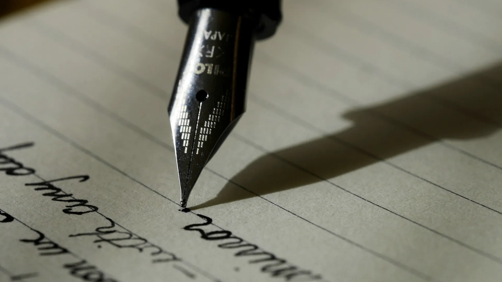 A fountain pen resting on a signed document in low, raking light